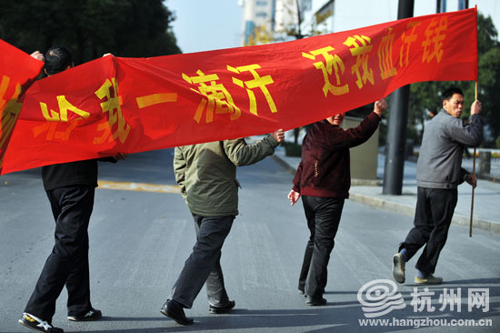 环城北路,举着横幅的农民工正在过马路.