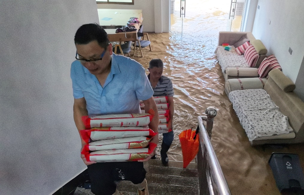 (眼见大水漫进了屋子,大家赶忙把位于一层的近40袋大米搬上二楼。) 配图5