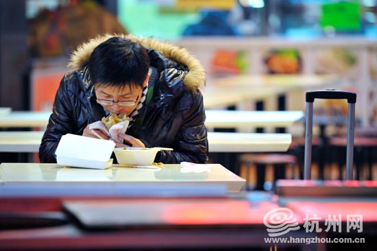 武林路一处快餐店里,带着拉杆箱的小伙子一个人在吃快餐.